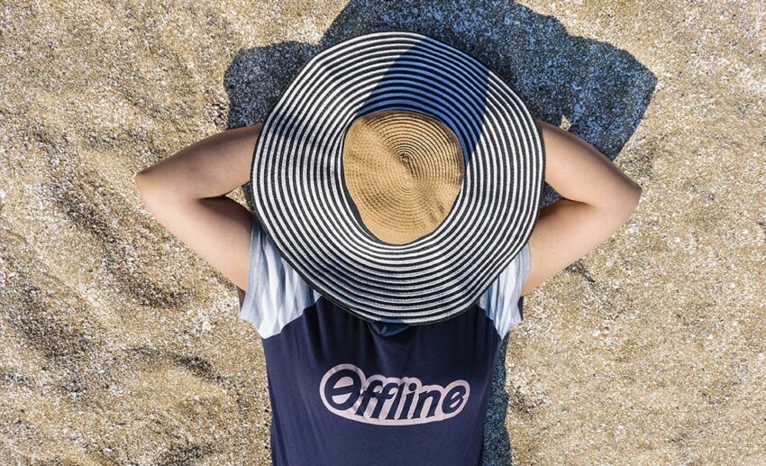 A woman relaxing on the sandy beach with a straw hat over her face, taking time to disconnect and rest.