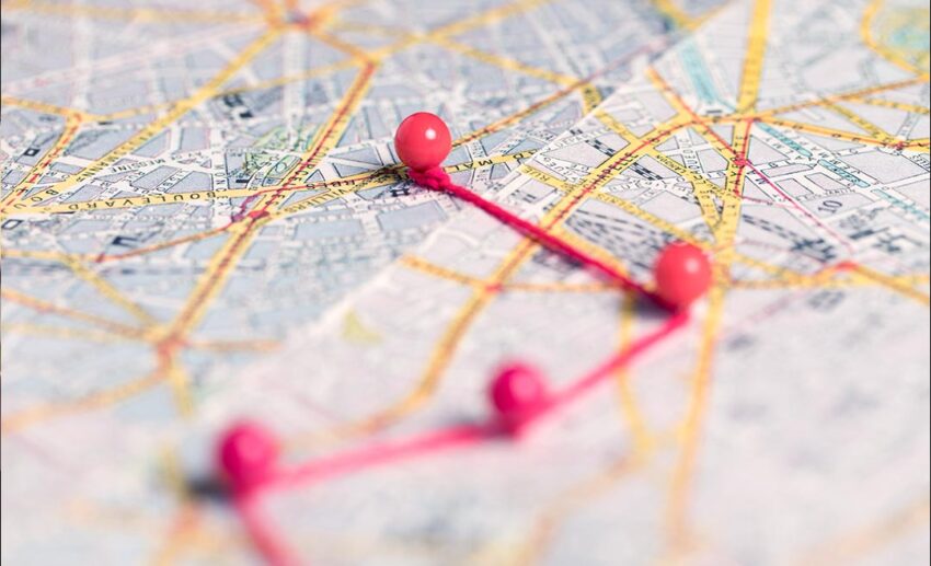 Close-up of blurred red location pins scattered across a road map, symbolising weekend travel planning.