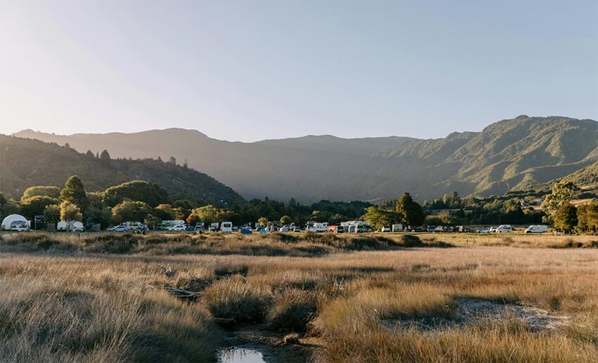 Campsite in a valley surrounded by mountains in Abel Tasman National Park, New Zealand.