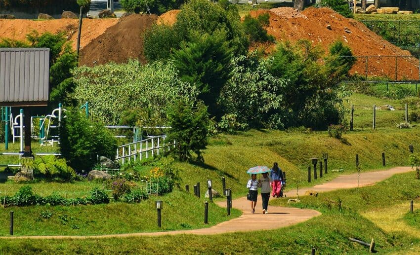 Green tea-country landscape with houses and people walking near Nuwara Eliya, Sri Lanka.