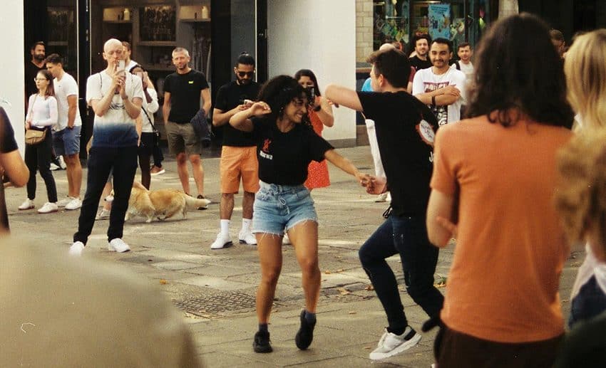People dancing outdoors on a public street in Norwich, UK, surrounded by an appreciative audience.