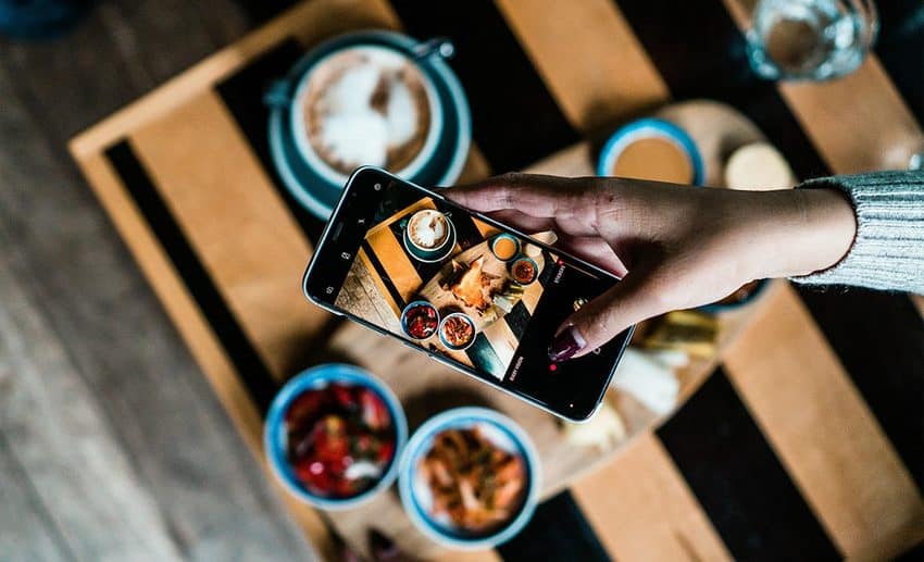 A traveller photographing a stylish artisanal dish at a trendy restaurant table.